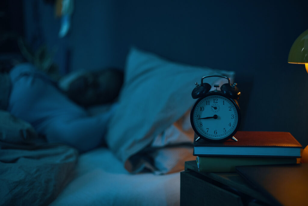 The importance of sleep for injury recovery 2 alarm clock on nightstand next to sleeping person 2026 03 25 03 35 29 utc